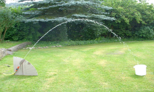 Mit einem Gartenschlauch wird ein parabelförmiger Wasserstrahl erzeugt.